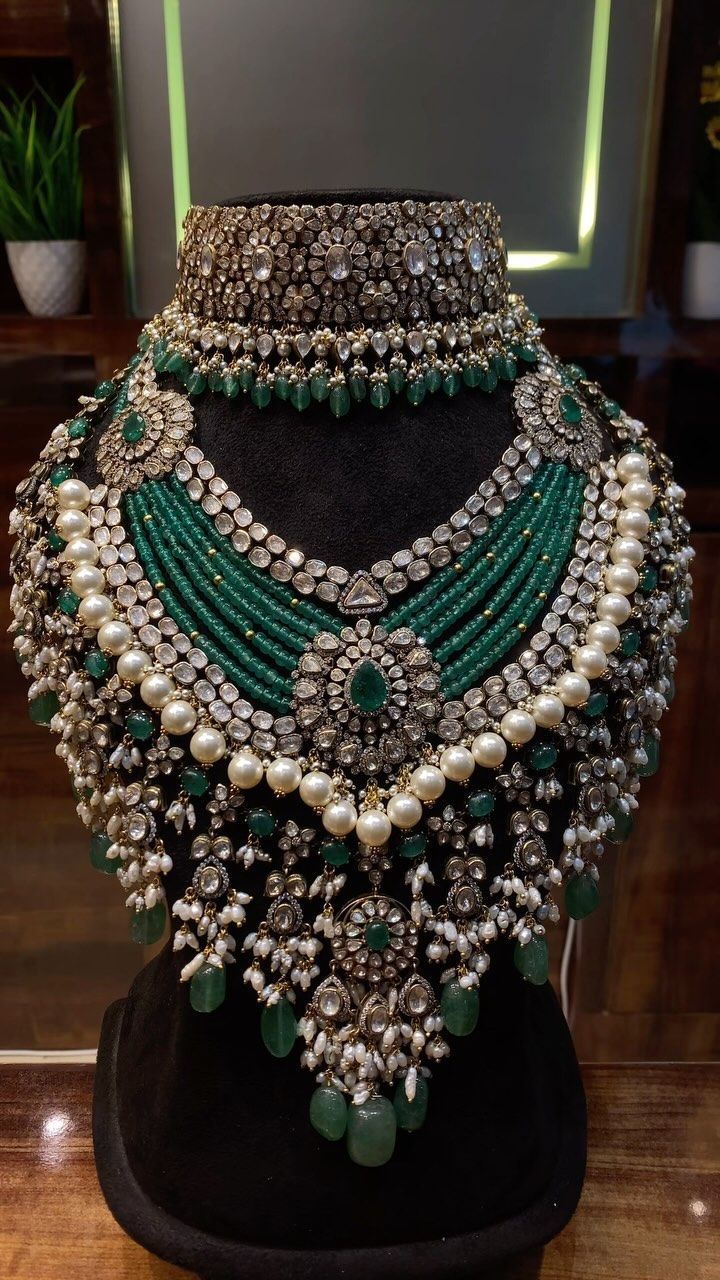 A statement necklace with green stones and pearls.